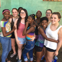students pose with younger children on a trip to Haiti