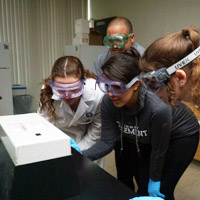 students in goggles gathered around lab equipment
