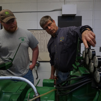 student and teacher working on a tractor
