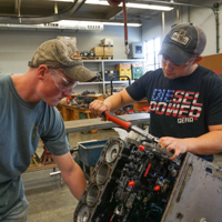 two students working on an engine